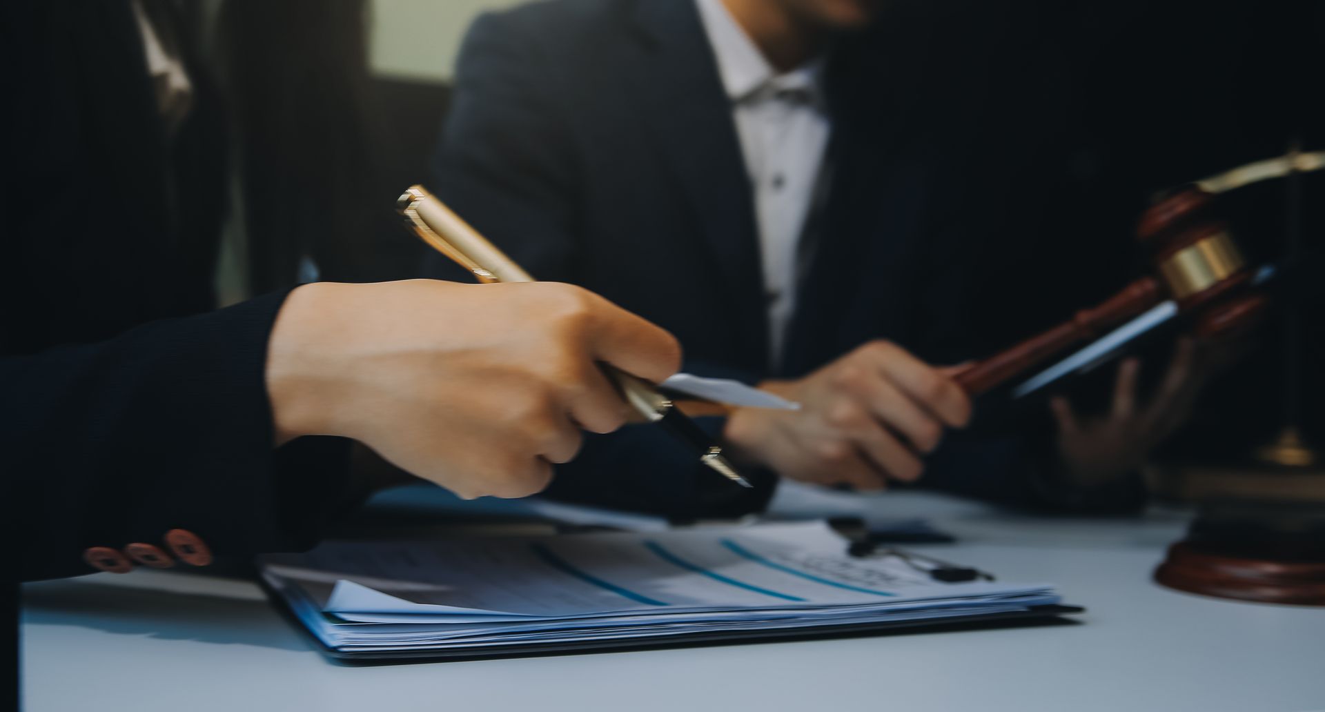 A woman is holding a pen and a gavel while sitting at a table.