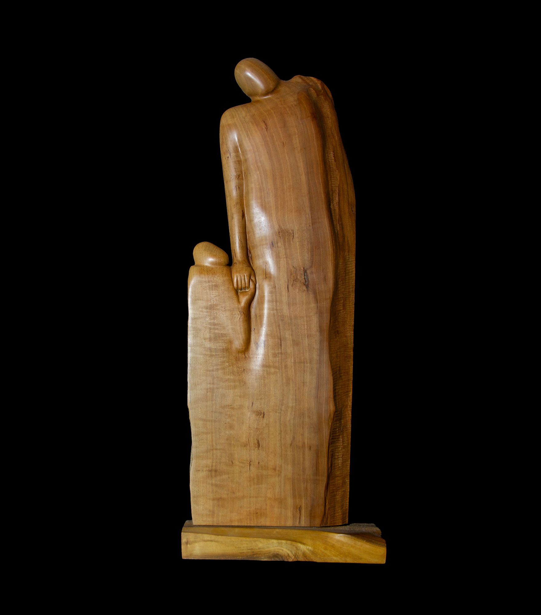 Eine Holzstatue eines Mannes, der auf schwarzem Hintergrund die Hand eines Kindes hält.