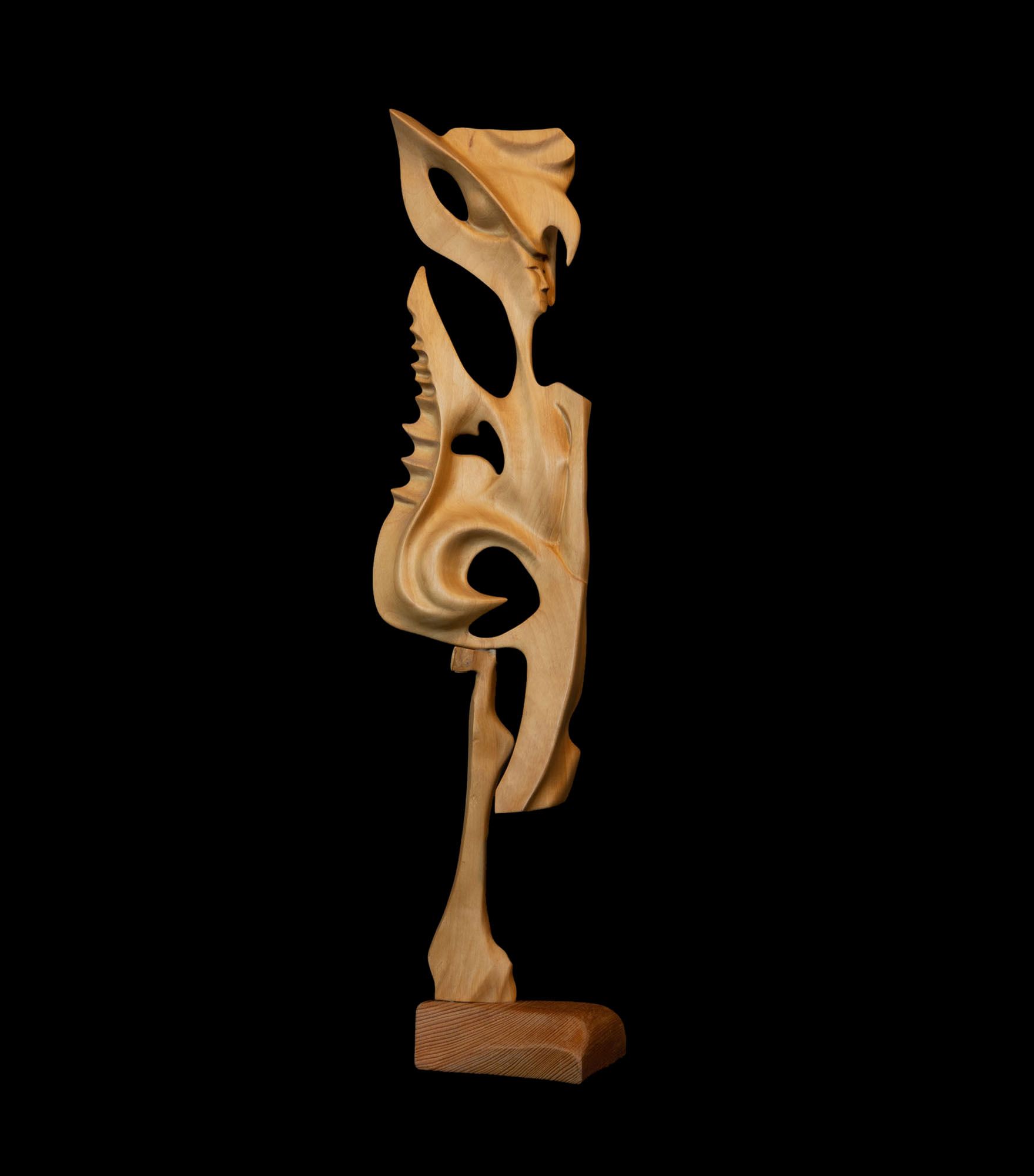Eine Holzskulptur steht vor einem schwarzen Hintergrund