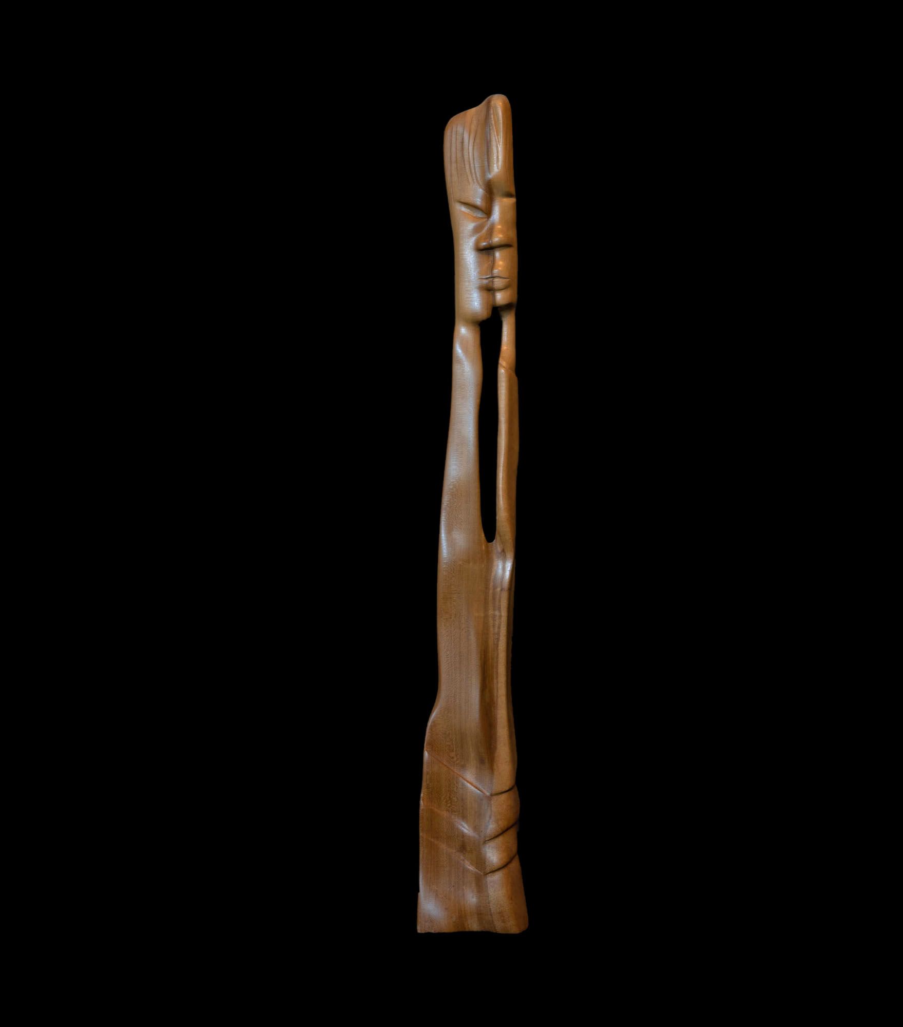 Eine Holzskulptur eines Männergesichts auf schwarzem Hintergrund.