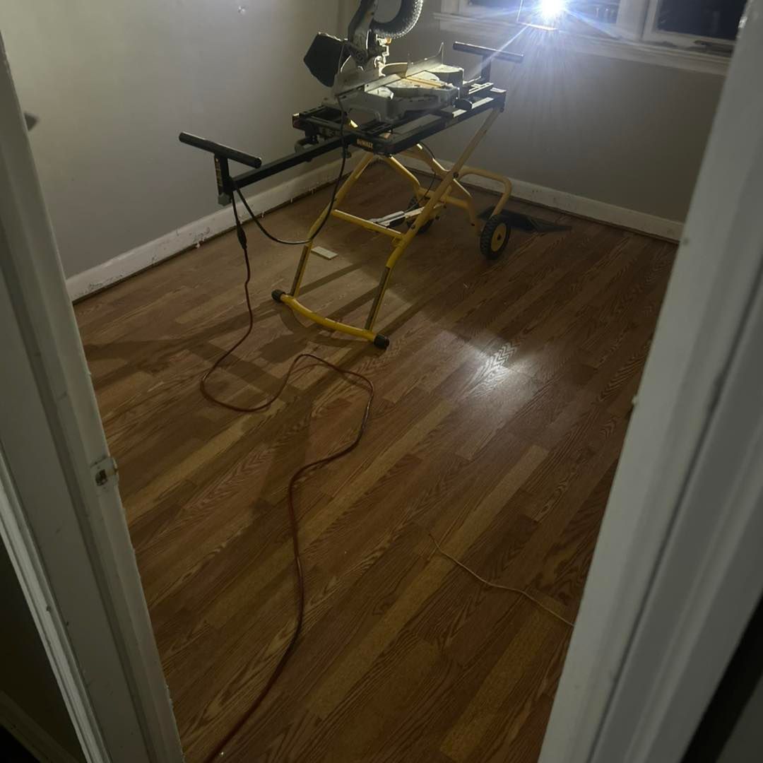 A small room with wood flooring, a yellow saw stand, and a miter saw.