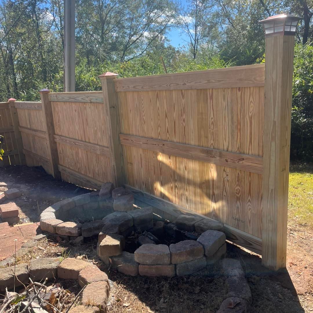 Wooden privacy fence, fire pit, and brick edging in a backyard setting.