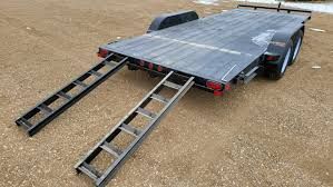 Car trailer with ramps on gravel.