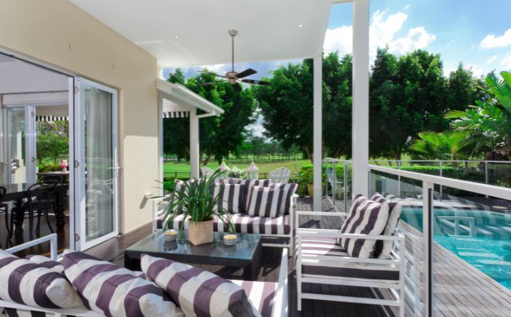 Luxurious poolside deck in Pomona, CA, featuring stylish striped furnishings and a serene view of lush greenery, embodying California's outdoor lifestyle.