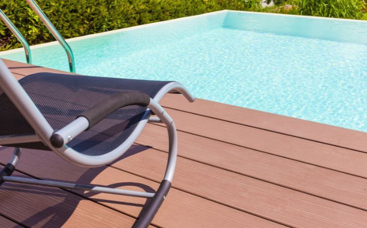 A modern pool deck in Pomona, CA, with composite decking in shades of brown, featuring a poolside lounge chair under the California sun.