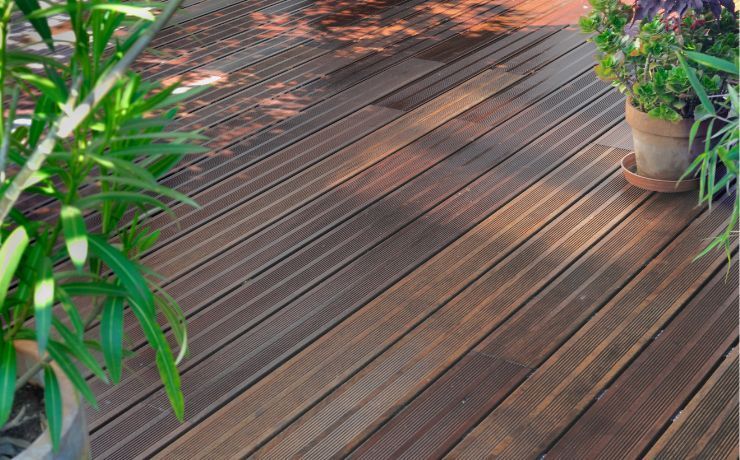 Warm-toned wooden deck with rich textures and a potted plant accentuating the natural beauty of a Pomona, California, backyard oasis.