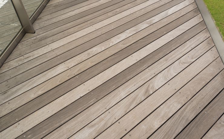 A close-up view of a newly constructed custom wooden deck with a contemporary design, featuring alternating light and dark brown planks in Pomona, CA.