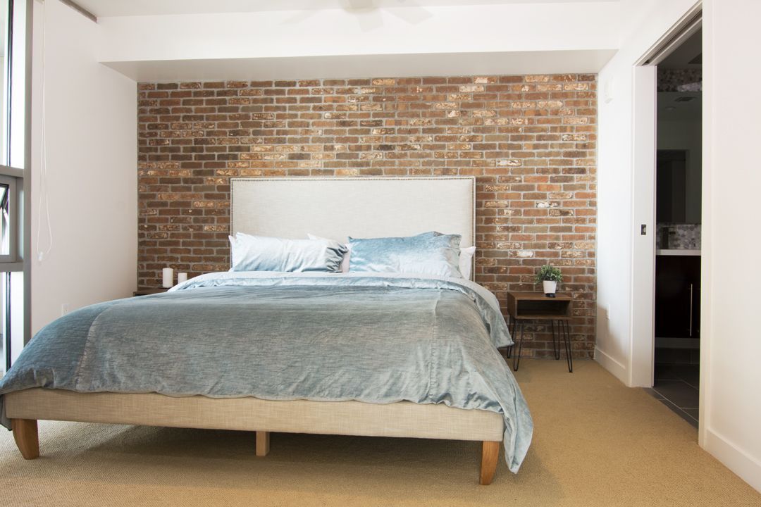 A bedroom with a bed and a brick wall.