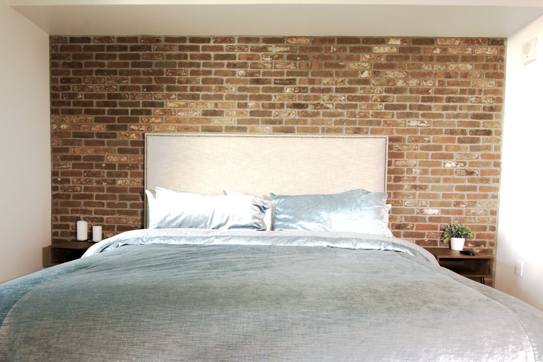 A bedroom with a bed and a brick wall
