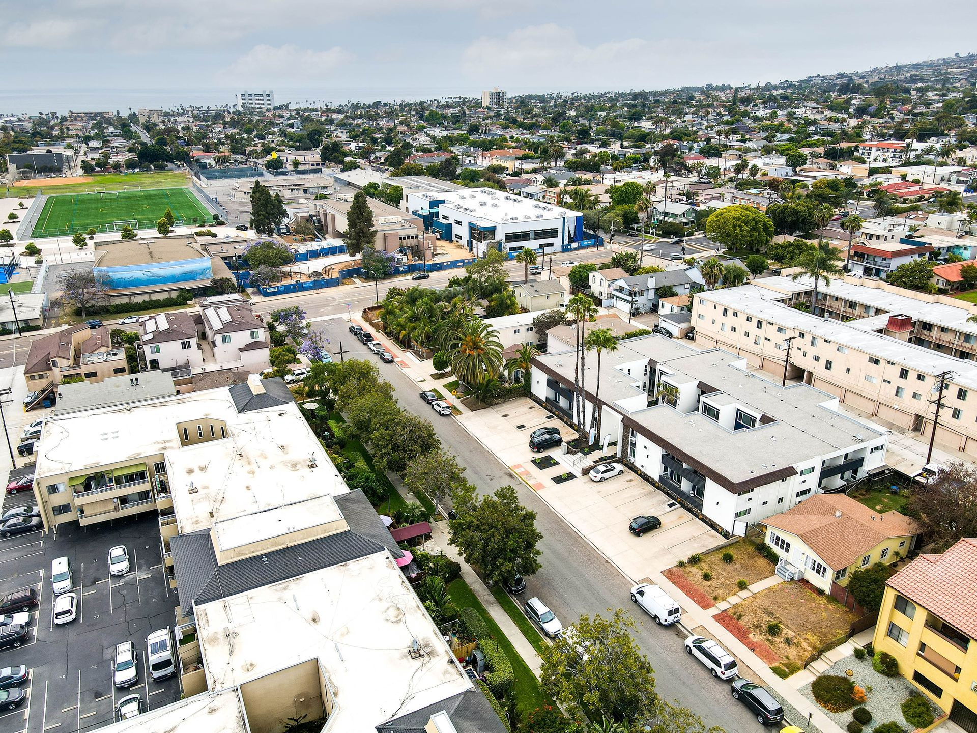 An aerial view of a city with lots of buildings and cars parked on the side of the road.