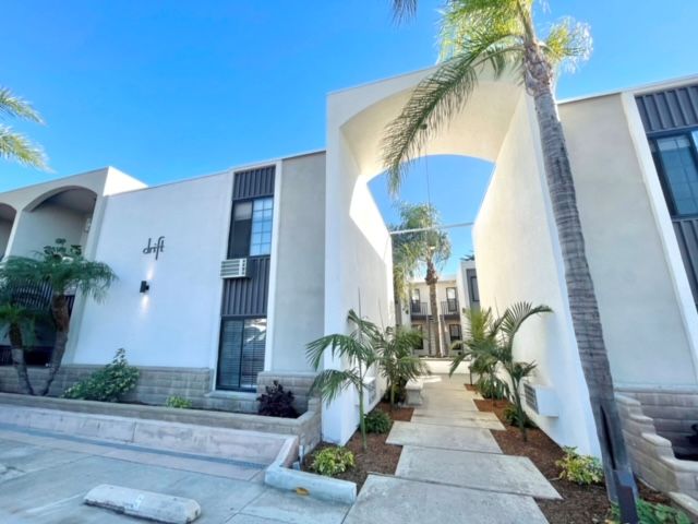 A white building with a palm tree in front of it