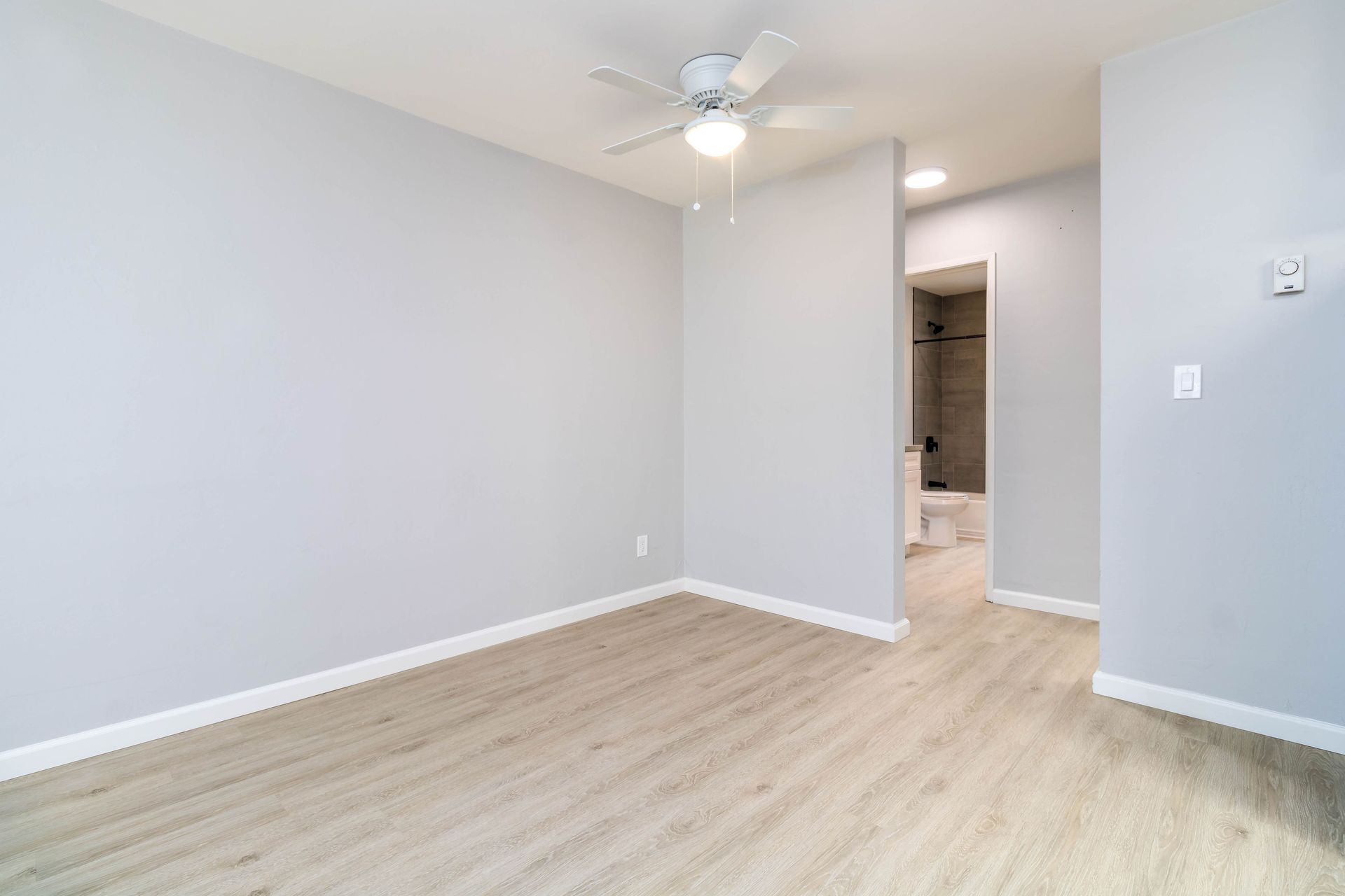 An empty bedroom with hardwood floors and a ceiling fan.