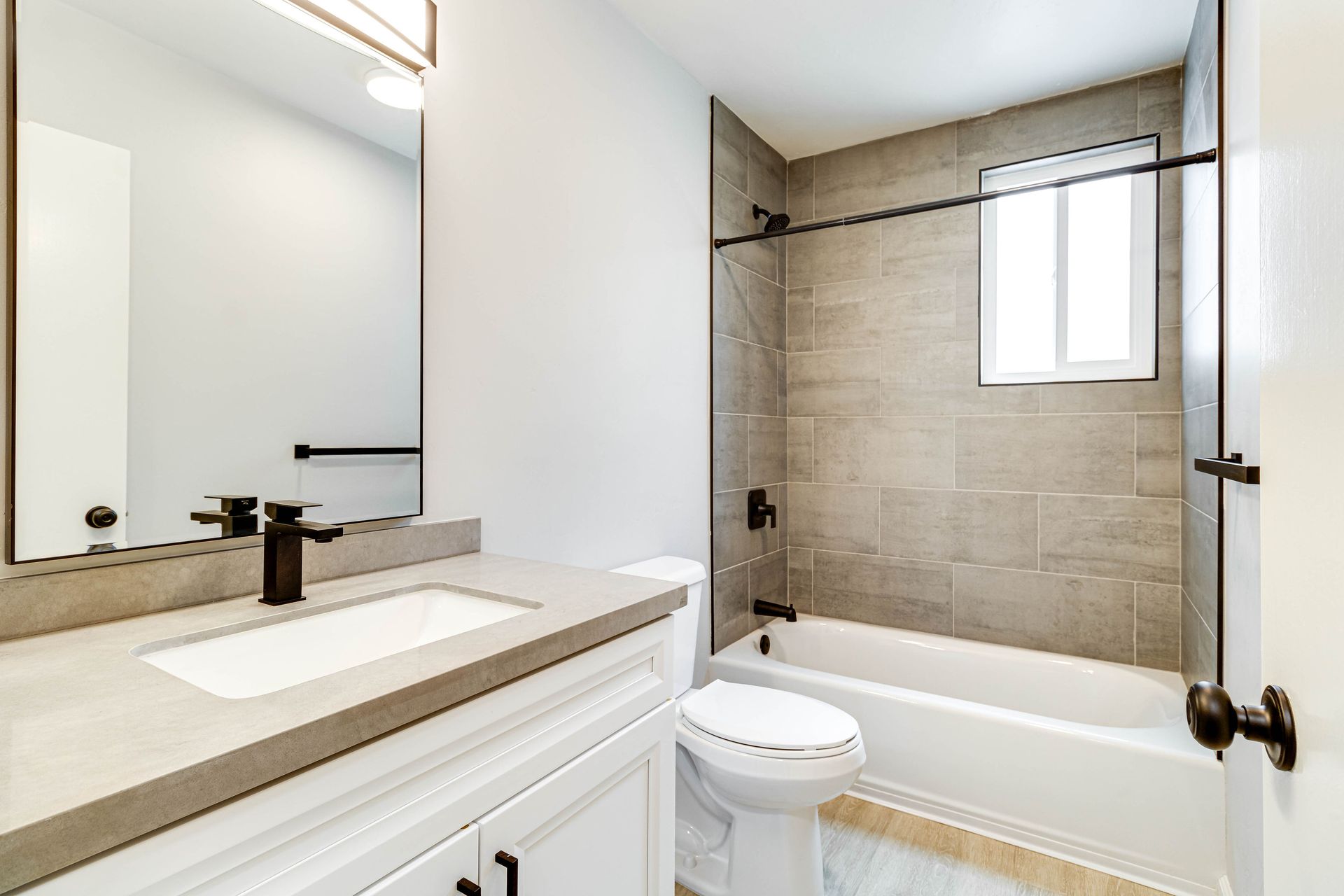 A bathroom with a toilet , sink , tub and mirror.