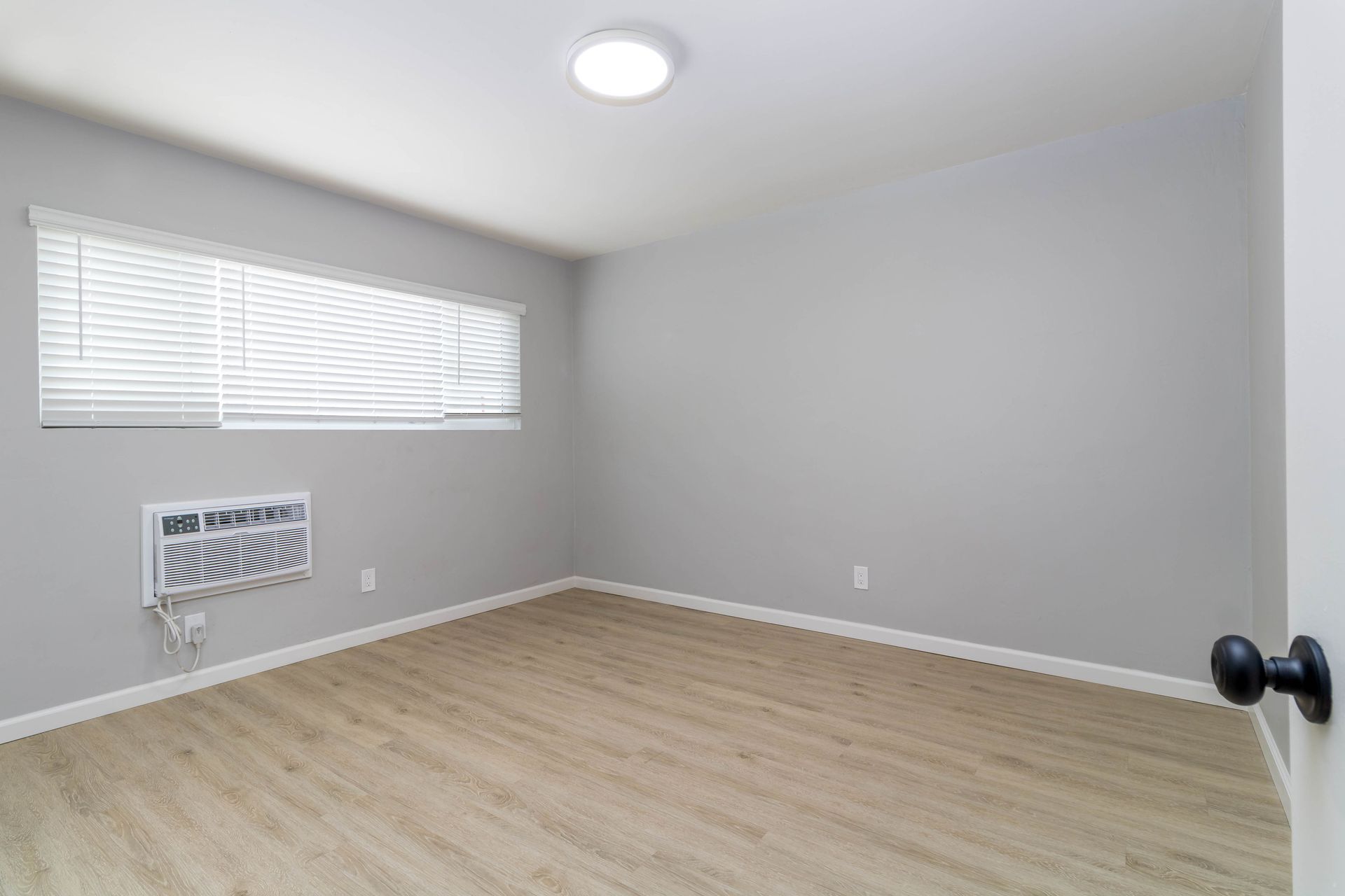 An empty room with hardwood floors and a window.