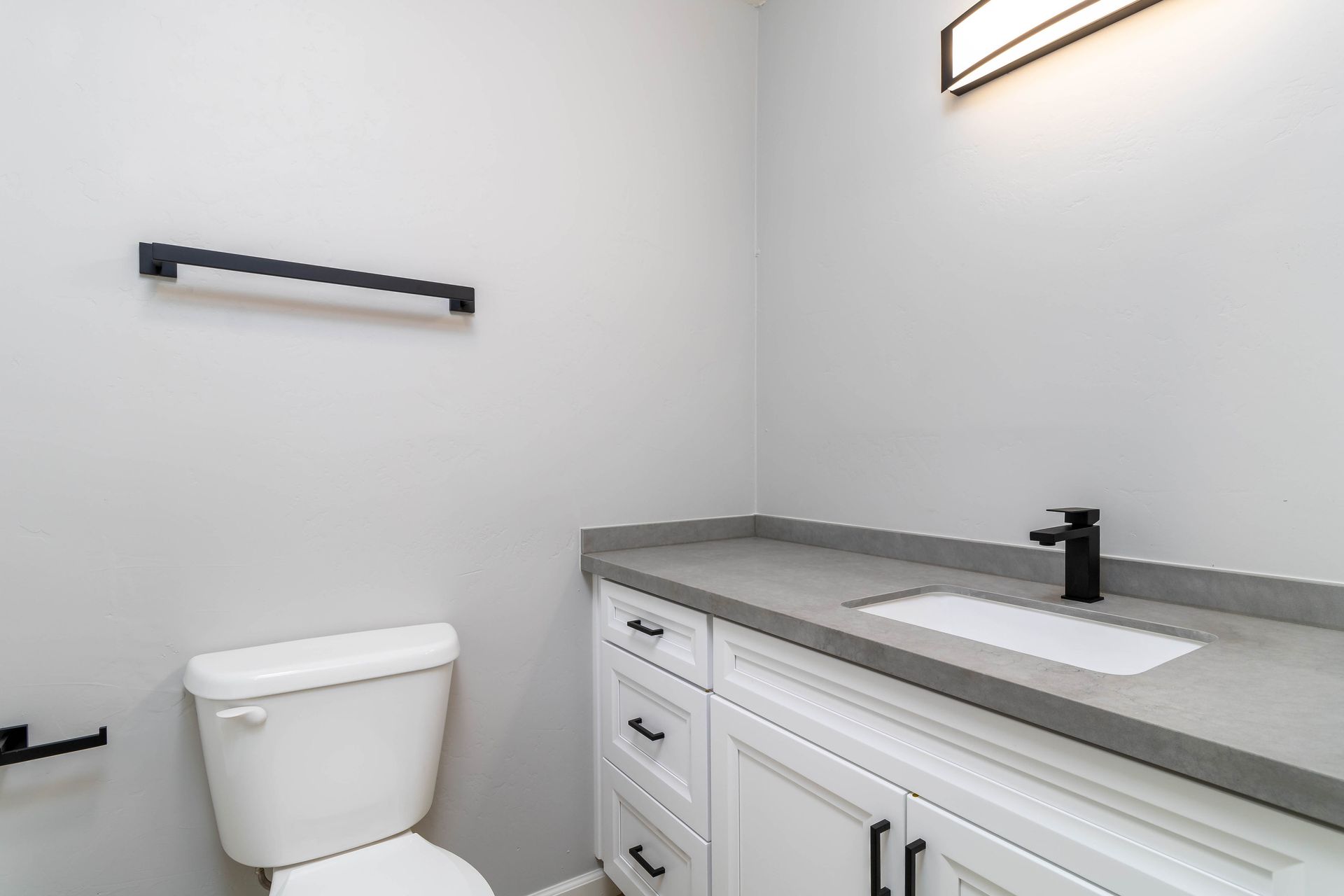 A bathroom with a toilet , sink and towel rack.