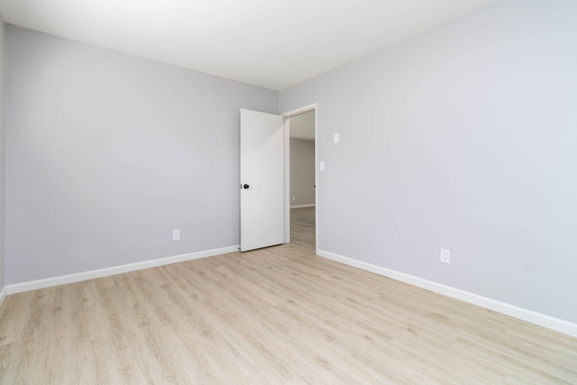 An empty bedroom with hardwood floors and white walls.