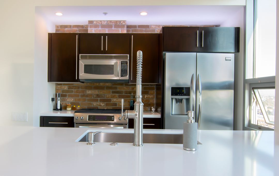 A kitchen with a sink , refrigerator , microwave and stove.