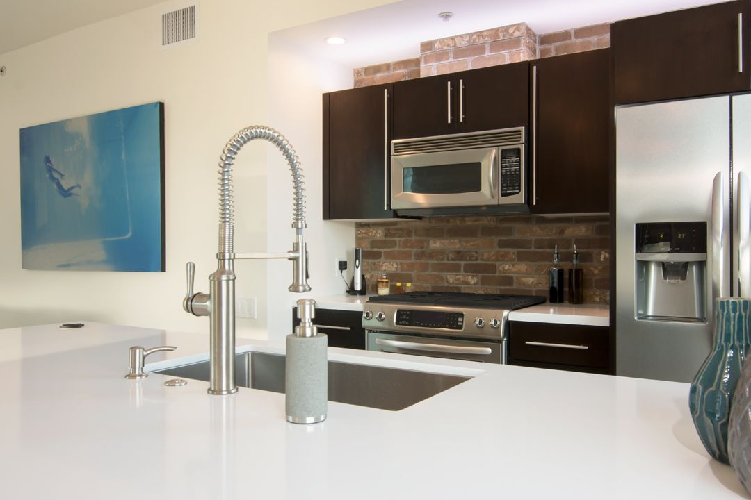 A kitchen with a sink , stove , refrigerator and microwave.