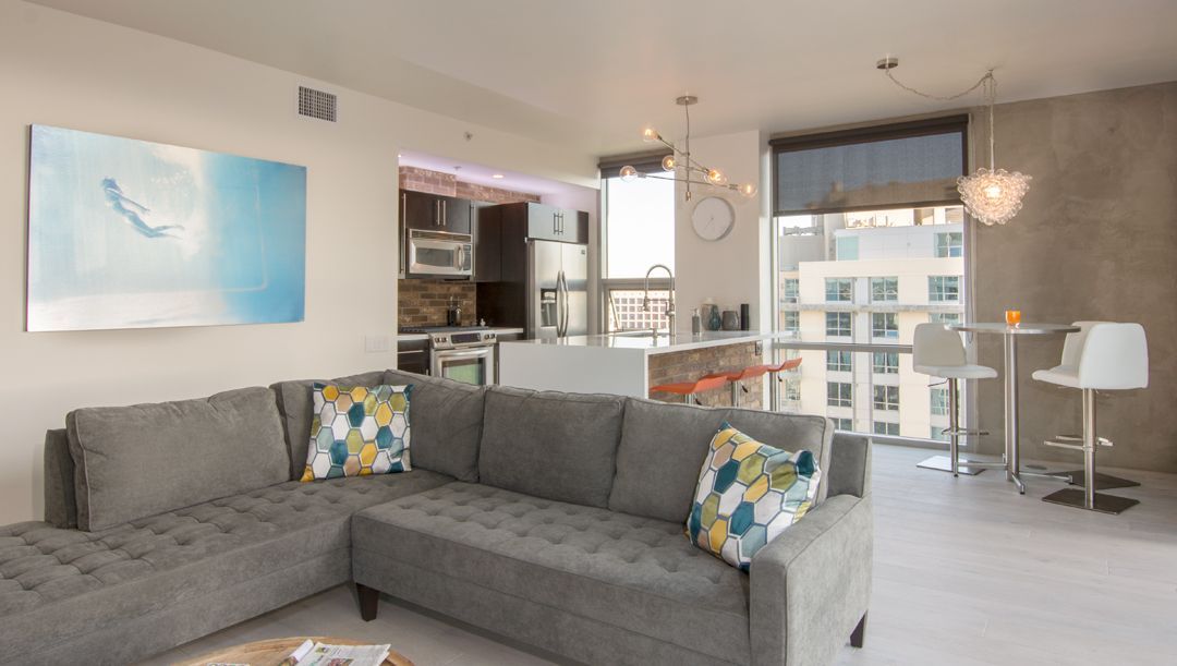 A living room with a large sectional couch and a painting on the wall.