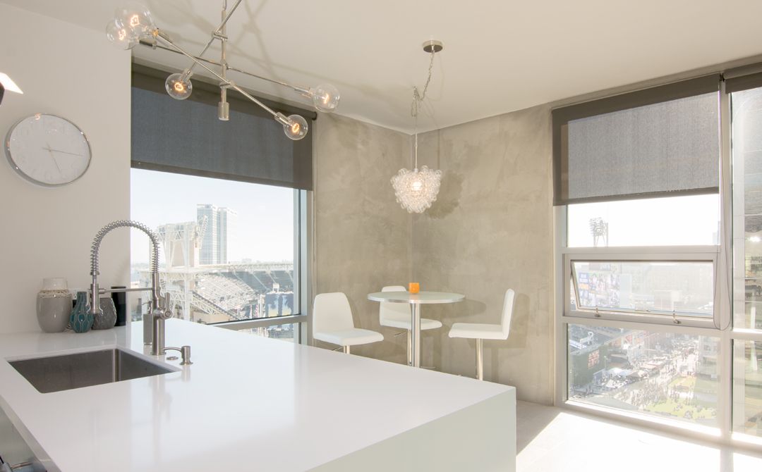 A kitchen with a sink , table and chairs and a large window.