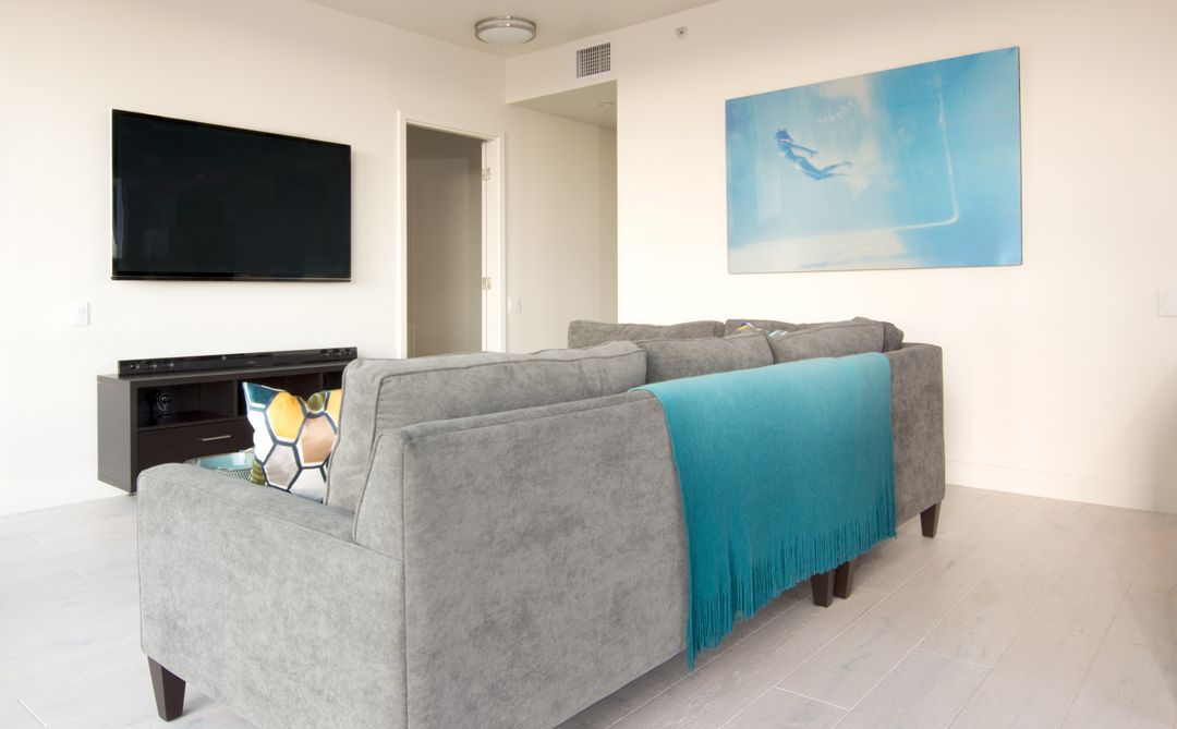 A living room with a couch , television , and painting on the wall.