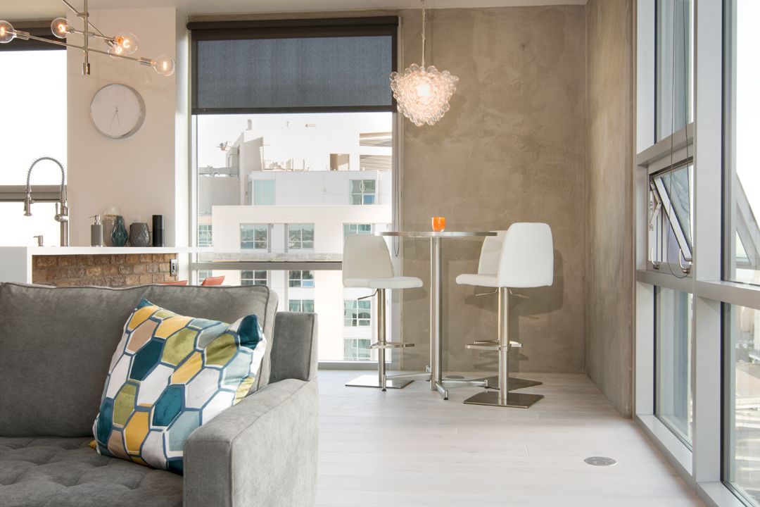 A living room with a couch , table and chairs and a large window.