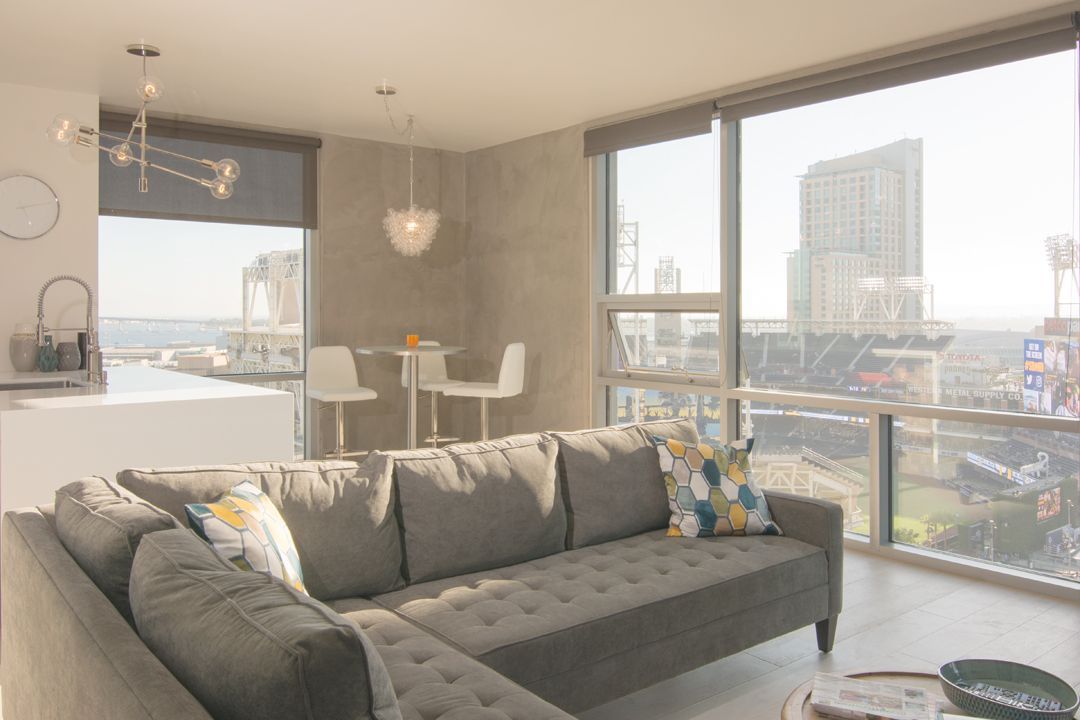 A living room with a couch and a large window with a view of a city.