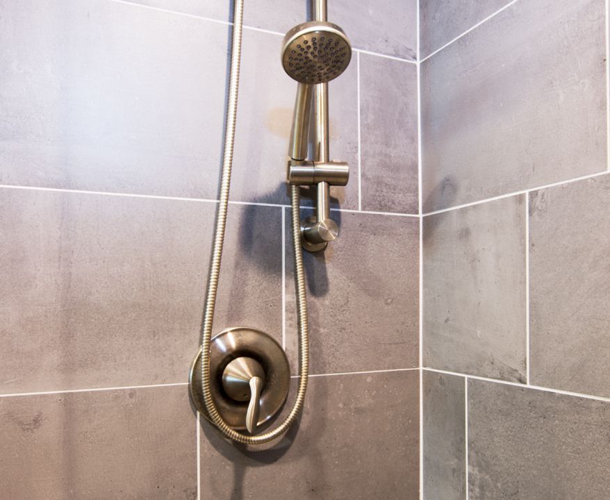 A shower head is hanging on a tiled wall in a bathroom.