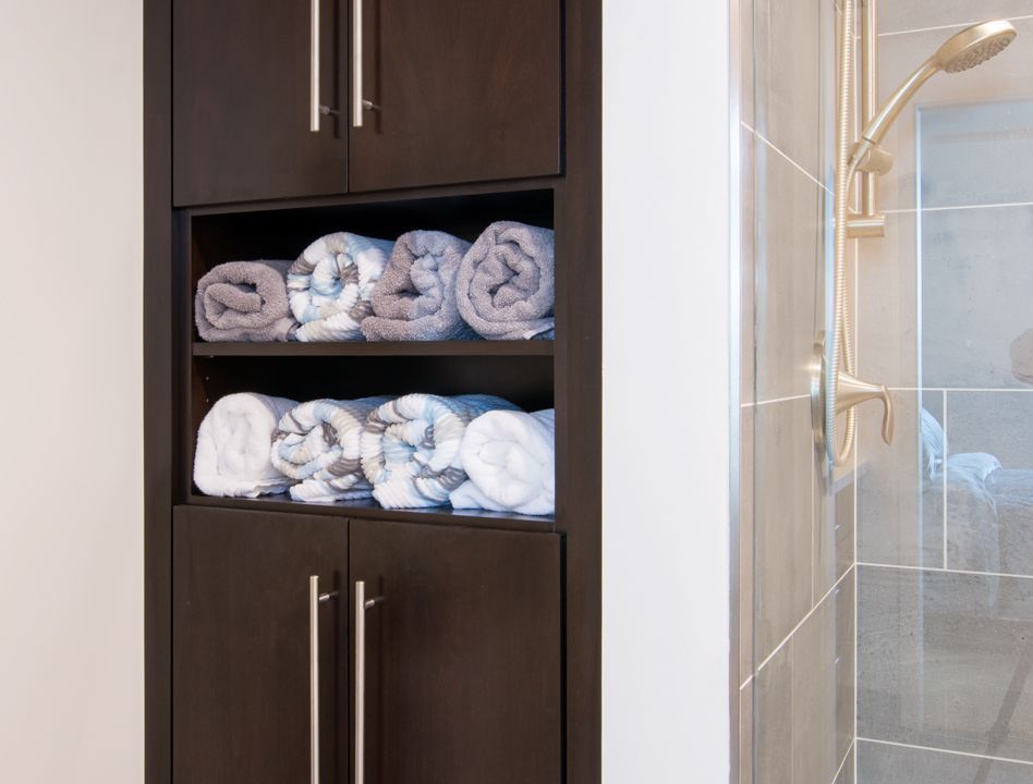A bathroom cabinet filled with towels next to a shower