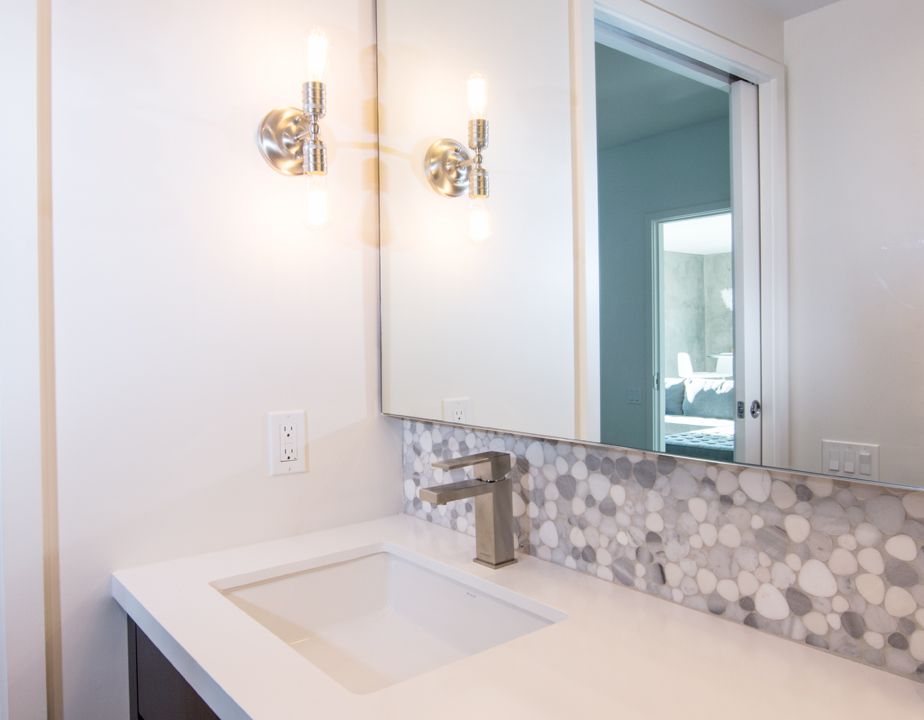 A bathroom with a sink , mirror and light fixtures.