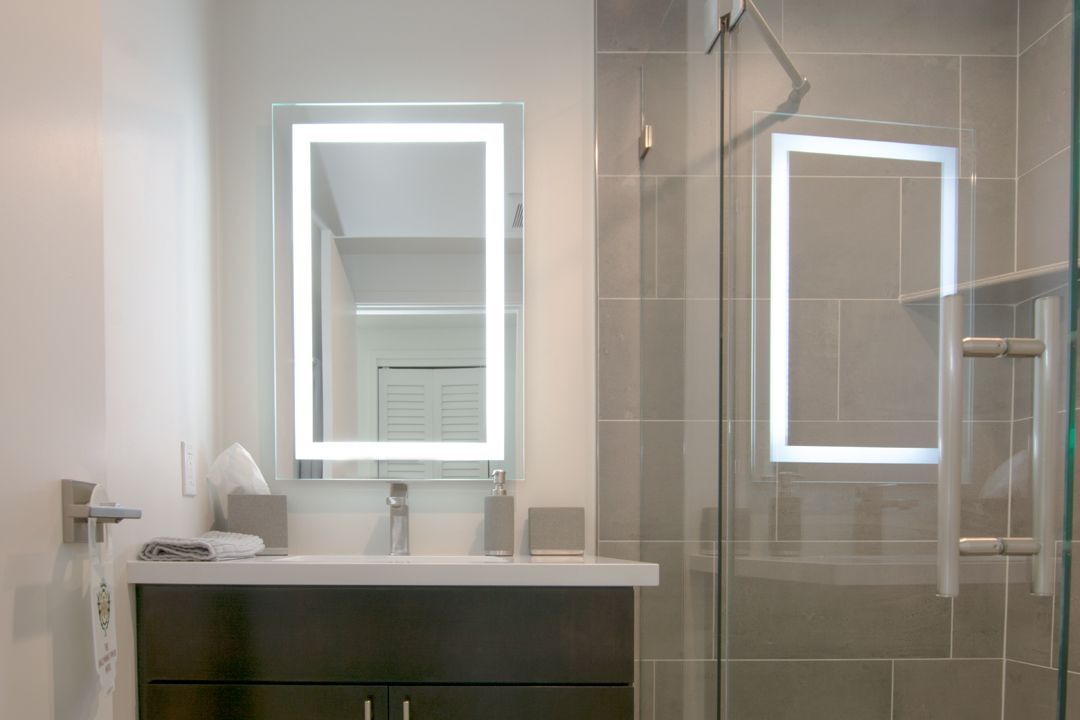 A bathroom with a sink , mirror and shower.