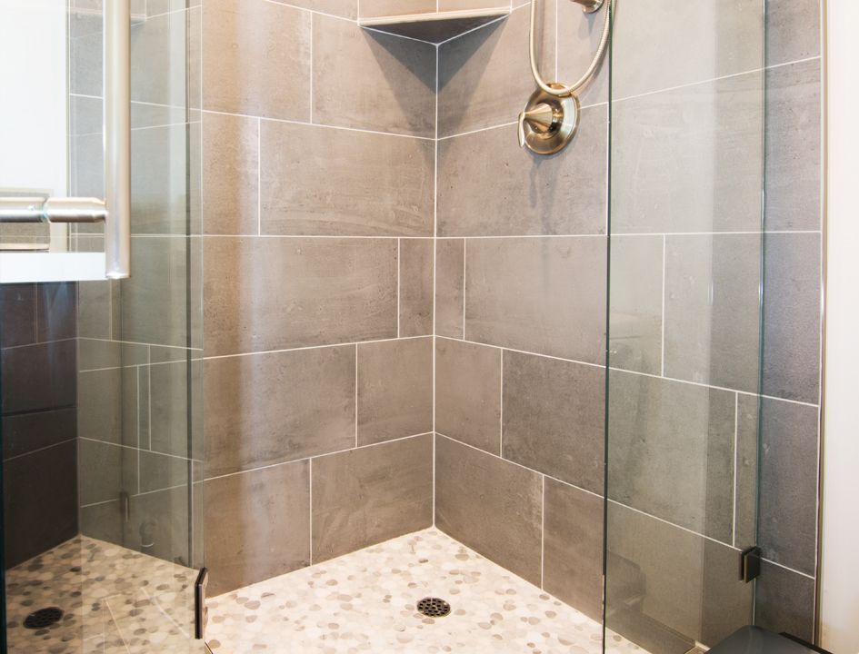 A bathroom with a walk in shower with a glass door.