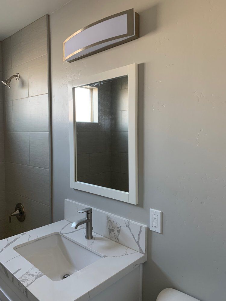 A bathroom with a sink , mirror and shower.