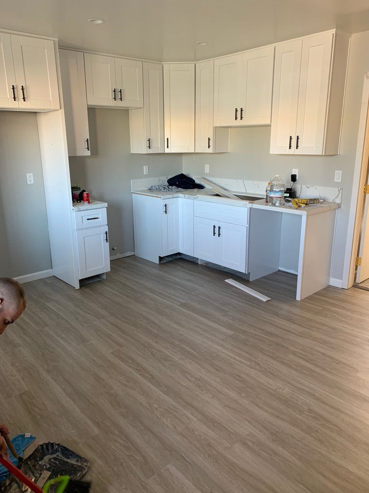A kitchen with white cabinets and wooden floors is being remodeled.