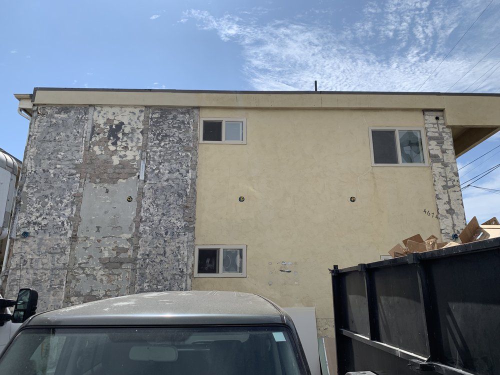 A car is parked in front of a building that is being demolished.
