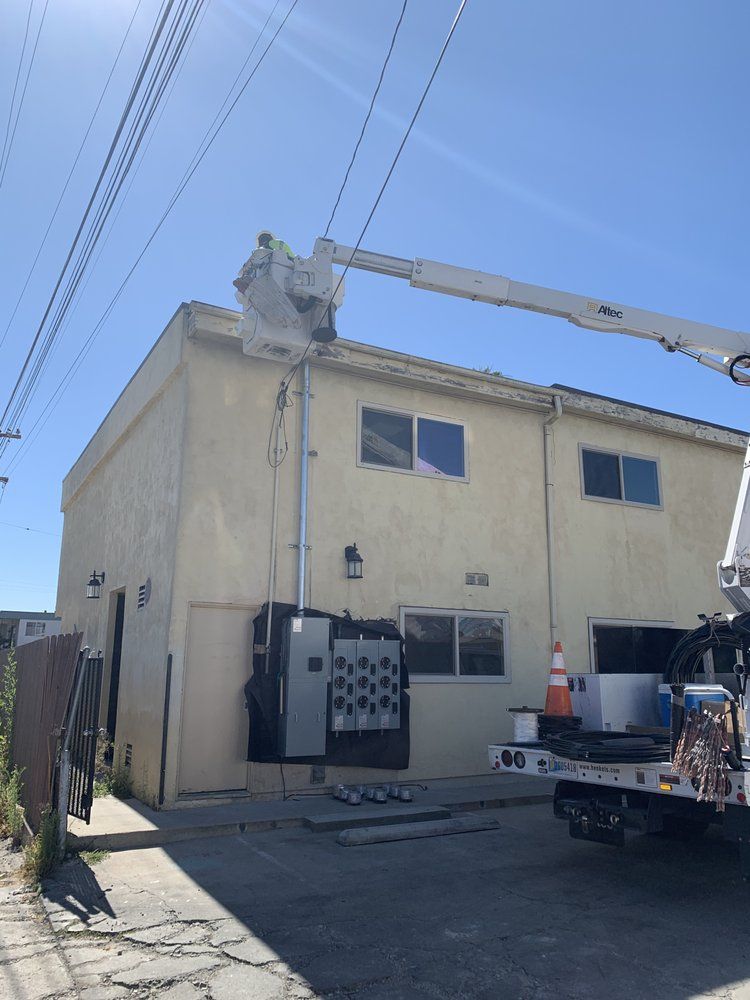 A white truck is parked in front of a building with a crane on top of it.