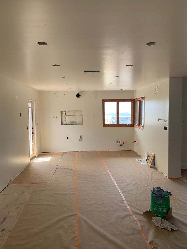 A large room with white walls and a green bag on the floor.