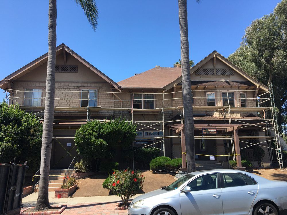 A car is parked in front of a house under construction.