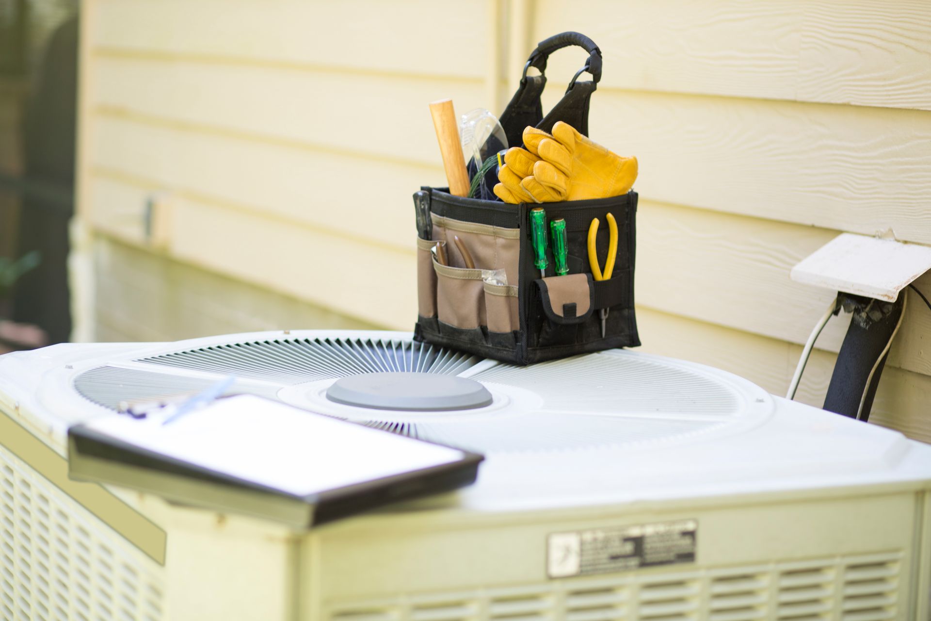 A box of tools is sitting on top of an air conditioner.