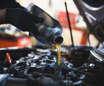 A person is pouring oil into a car engine.