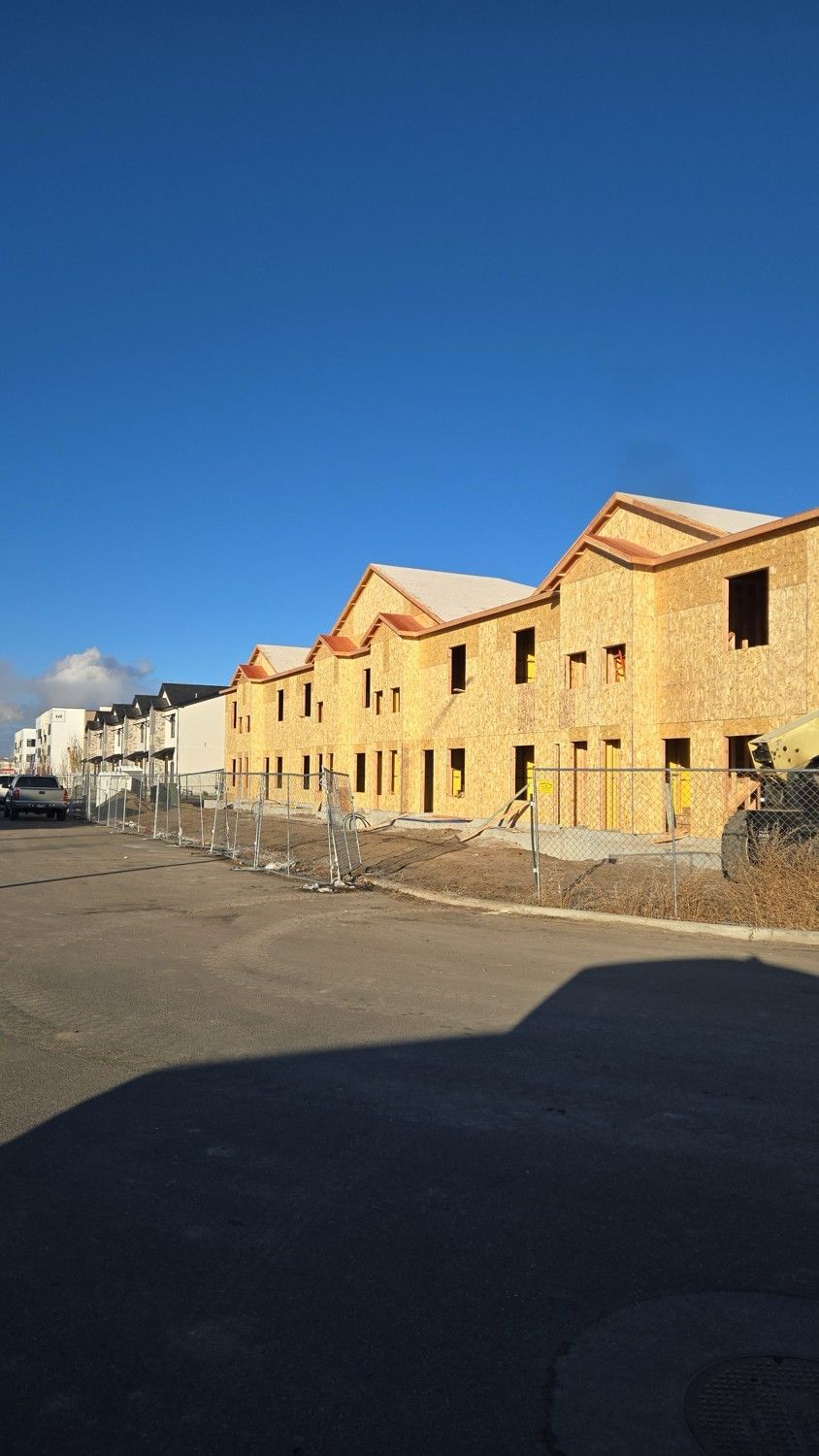 Row of wood-framed buildings under construction with blue sky background.