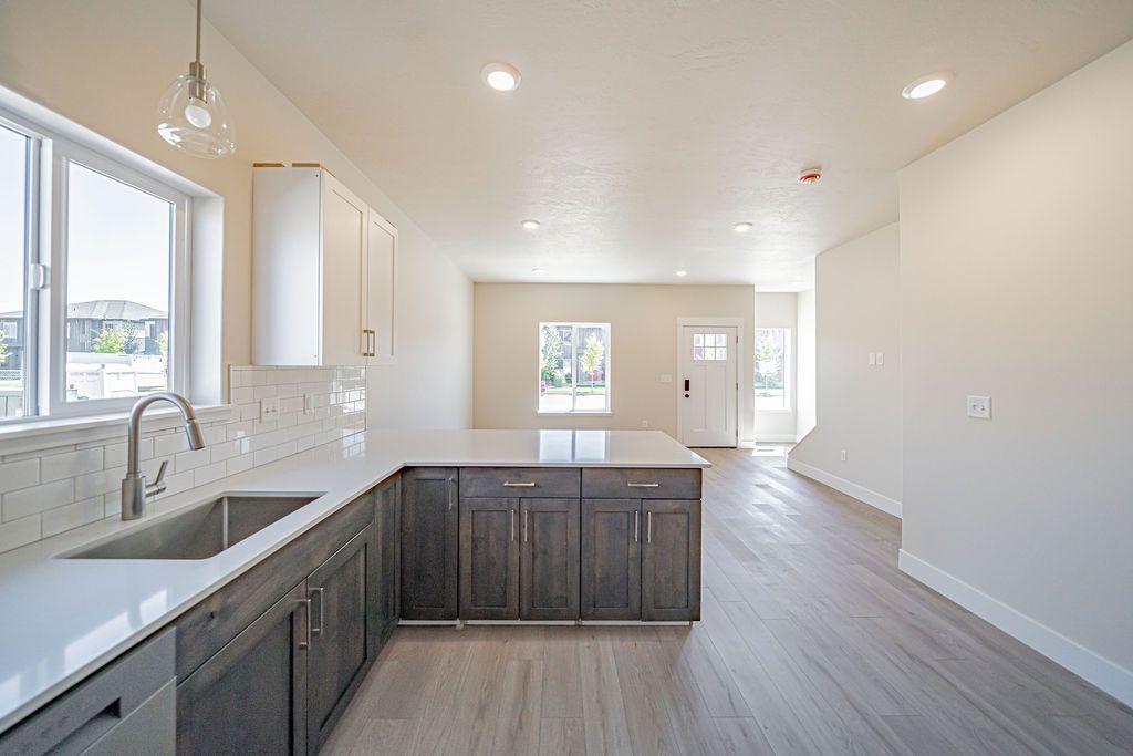 Modern kitchen with island, white countertops, gray cabinets, and light gray flooring.