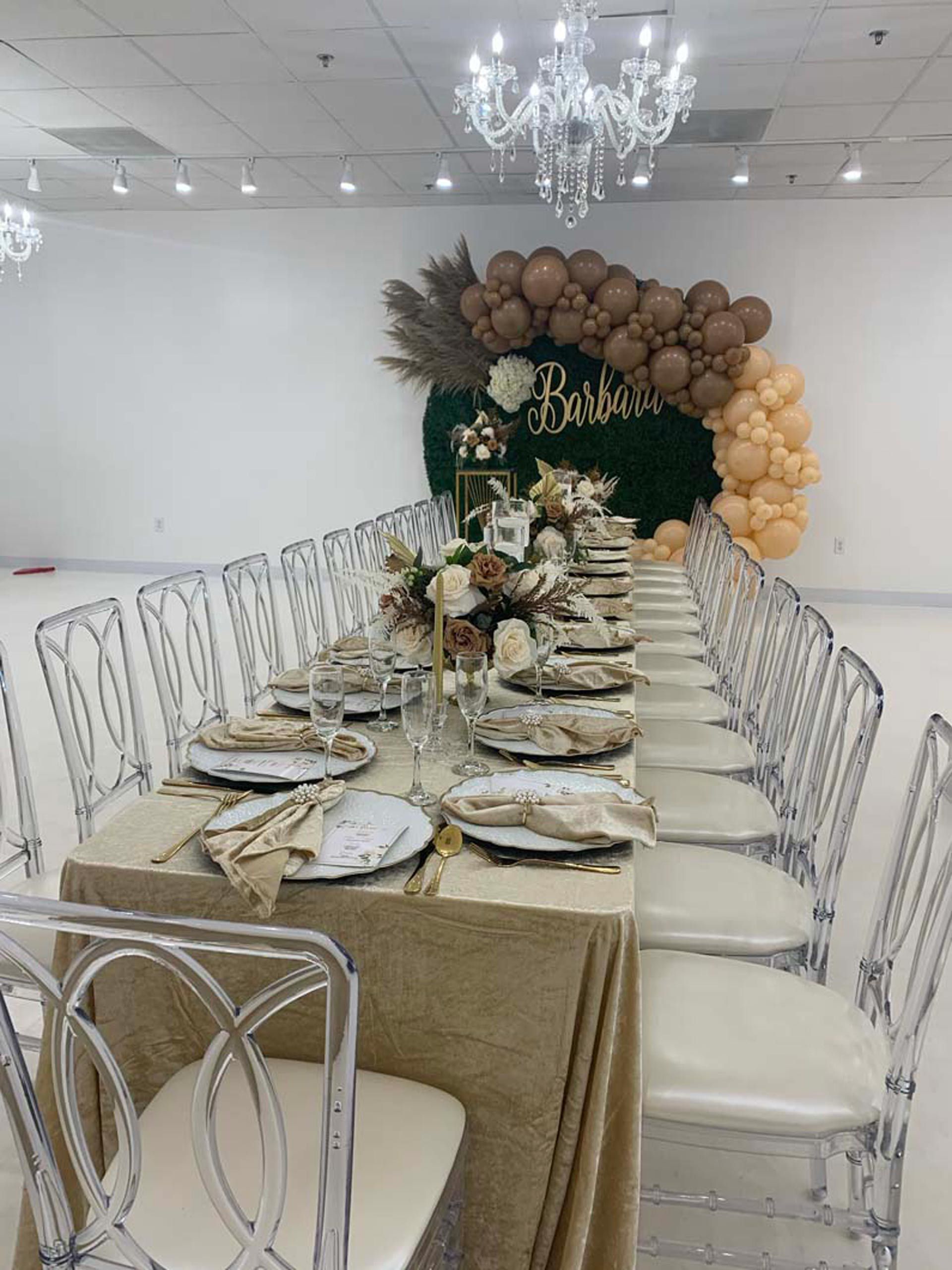 A long table with clear chairs and plates on it in a room
