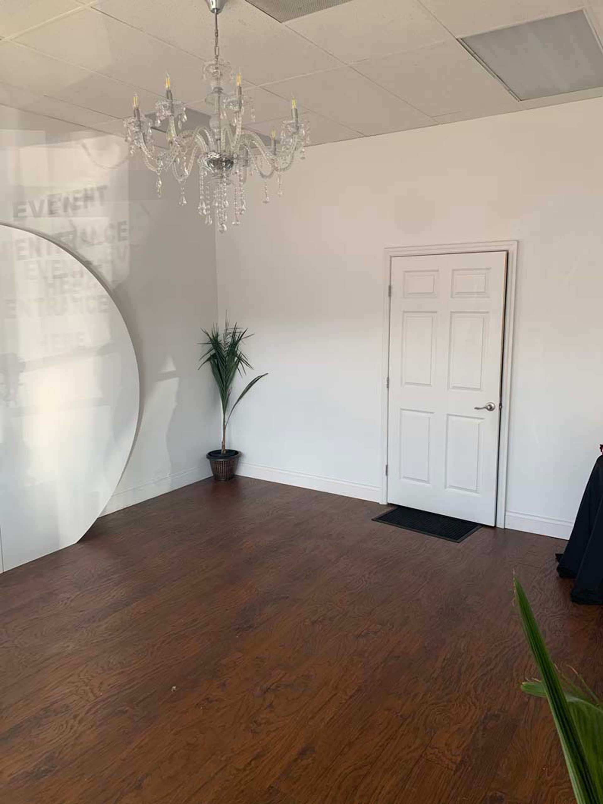 An empty room with a chandelier hanging from the ceiling and a door