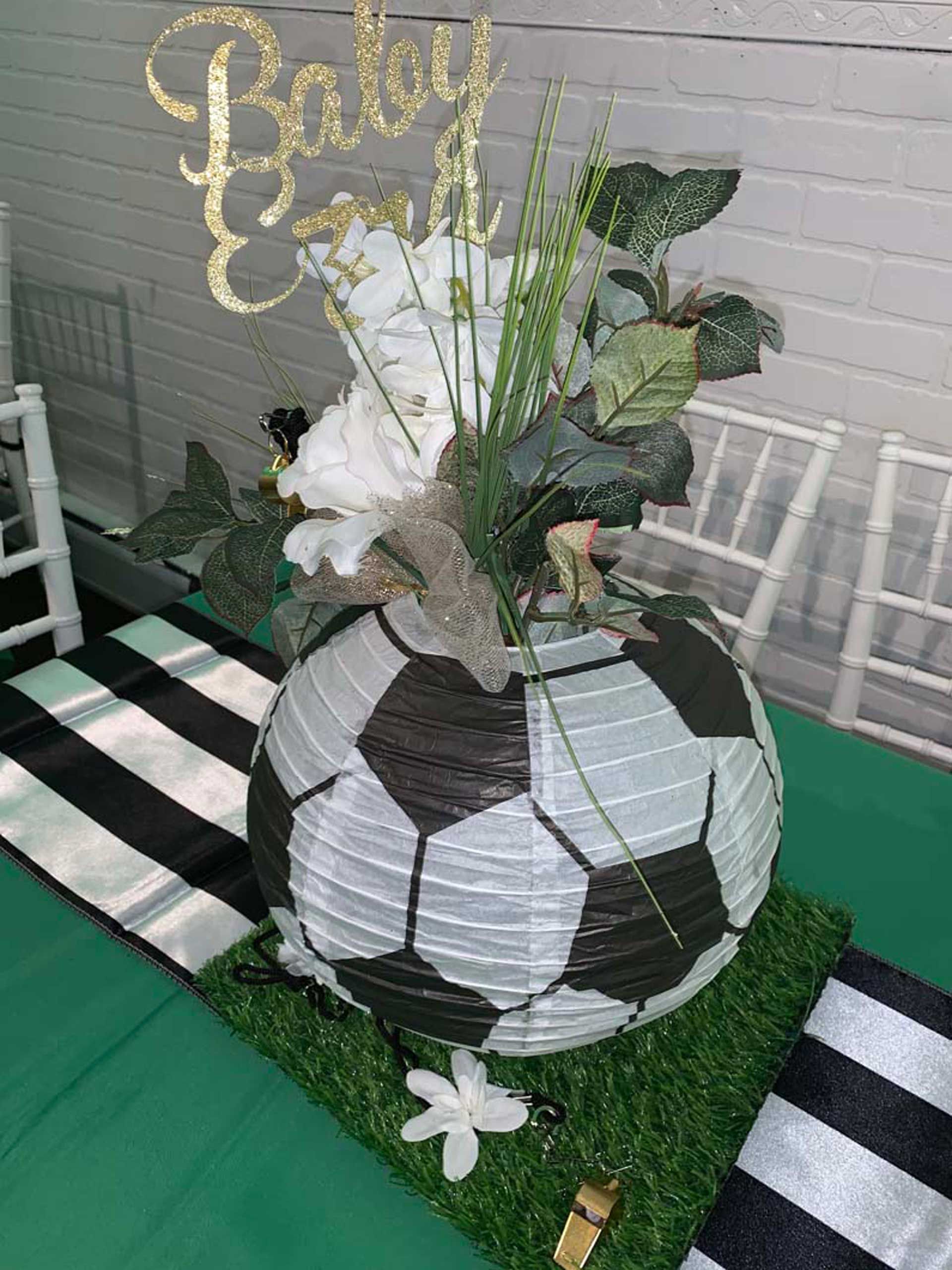 A soccer ball is sitting on top of a table with flowers in it