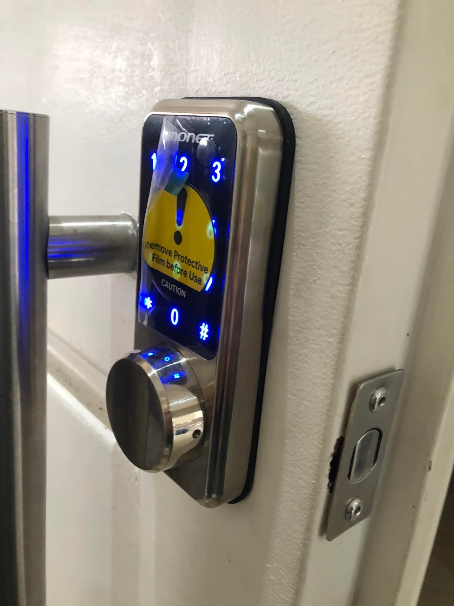 Cerradura inteligente en una puerta blanca con un teclado circular, una perilla y una etiqueta de advertencia en la pantalla.