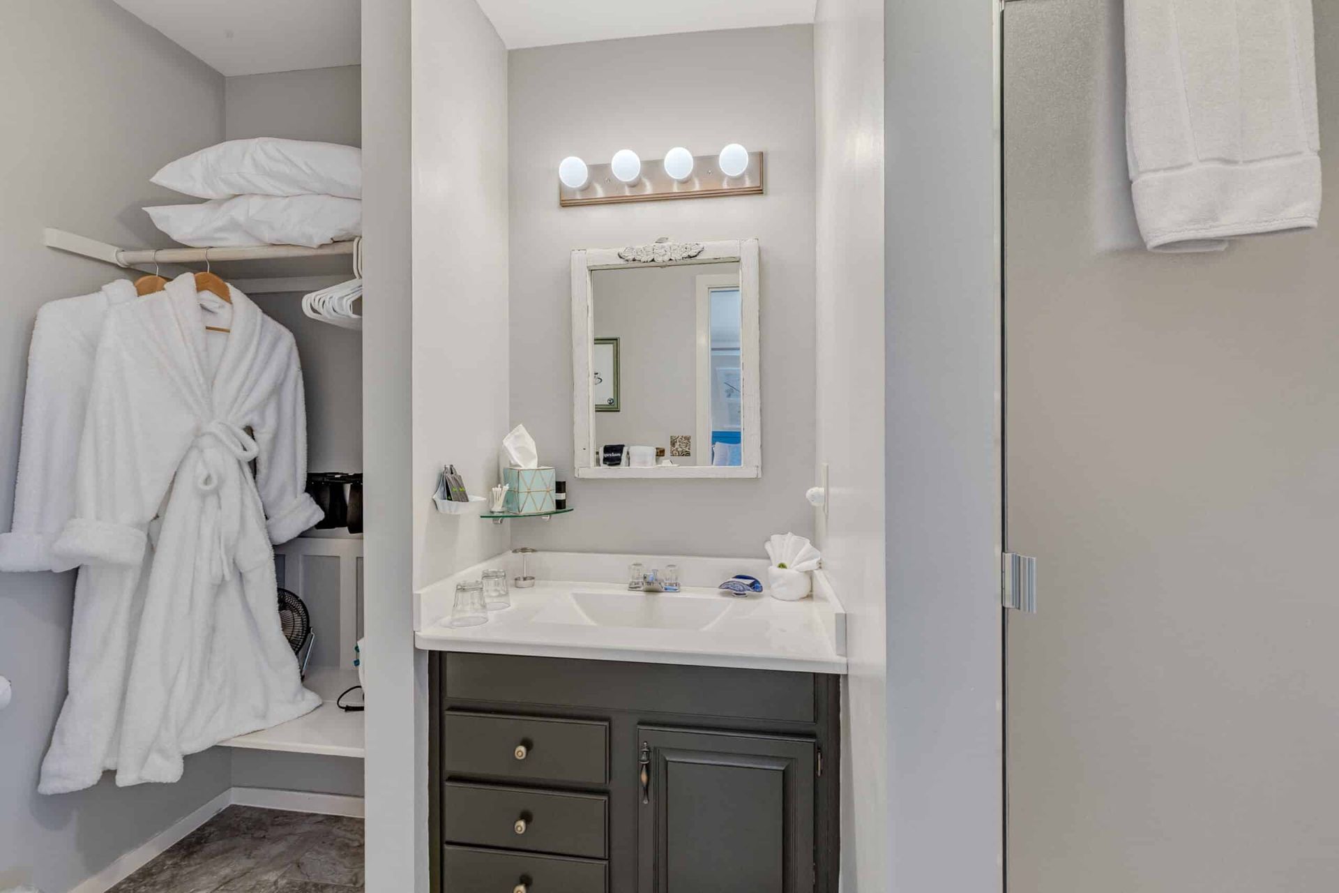 A bathroom with a sink , mirror and robe hanging on the wall.