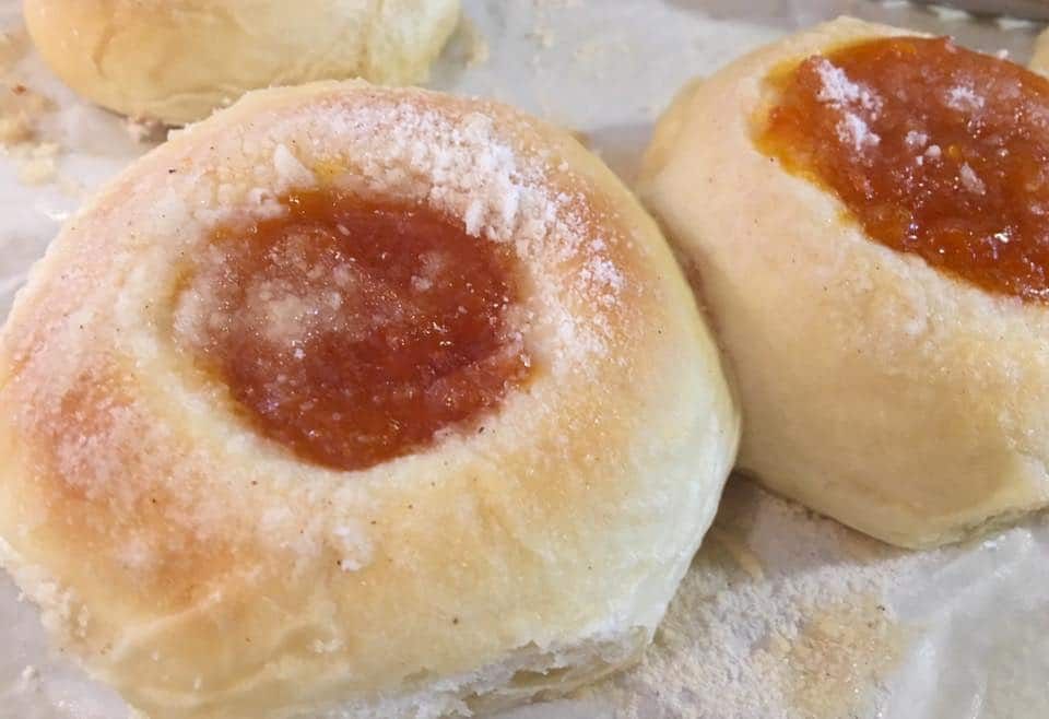 Two rolls with jam on them are sitting on a table.