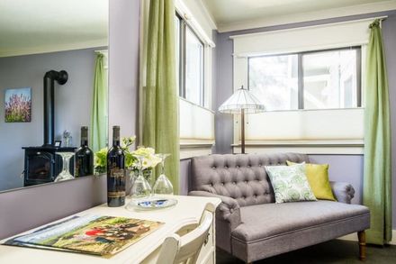 A living room with a couch and a table with a bottle of wine on it.