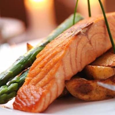 A white plate topped with salmon potatoes and asparagus